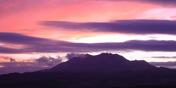 the silhouette of a mountain against the sun set