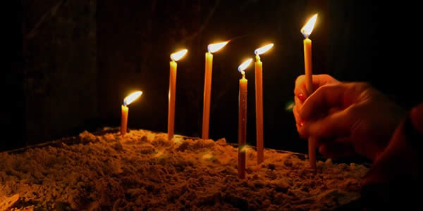 a woman placing candles in prayer