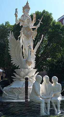 Aa statue of saraswati behind three young persons reading