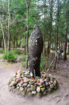 a stone statue of a goddess surrounded by candles and small offerings
