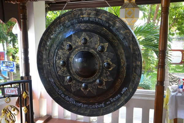 a large gong suspended from the ceiling of an outdoor porch or gazebo