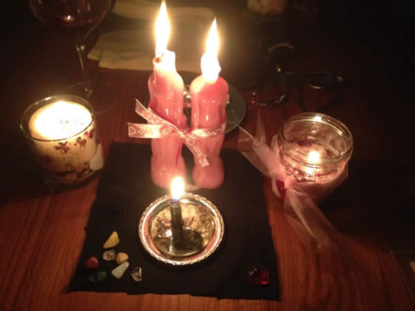 Valentine's Two lit figure candles on a black cloth melting into each other