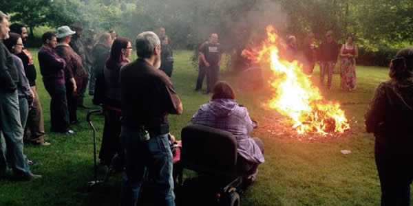 a group of people around a bonfire in the afternoon