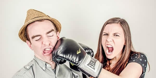 a woman wearing boxing gloves comically punching a man in the face