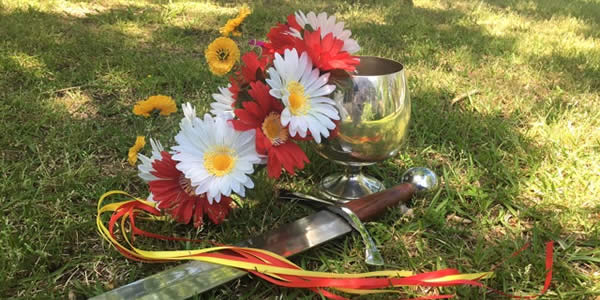 a wreath, chalice, and blade placed on the ground outside