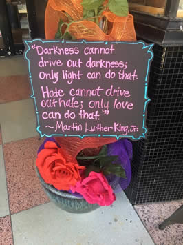 a sign reading "Darkness cannot drive out darkness; only light can do that. Hate cannot drive out hate; only love can do that" by Dr. Martin Luther King, Jr.