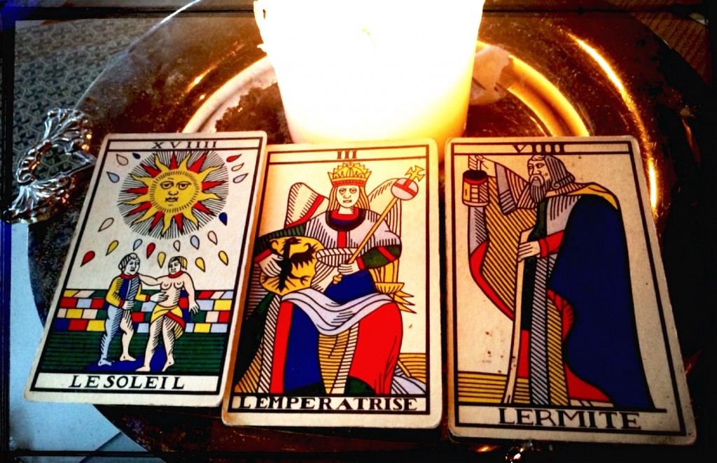 a spread of three tarot cards: the sun, the emperor, and the hermit