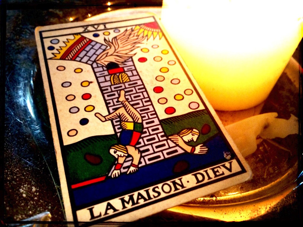 a tarot card, the Tower, next to a lit candle