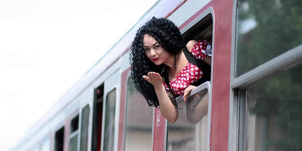 a woman leans out the window of a train and blows a kiss
