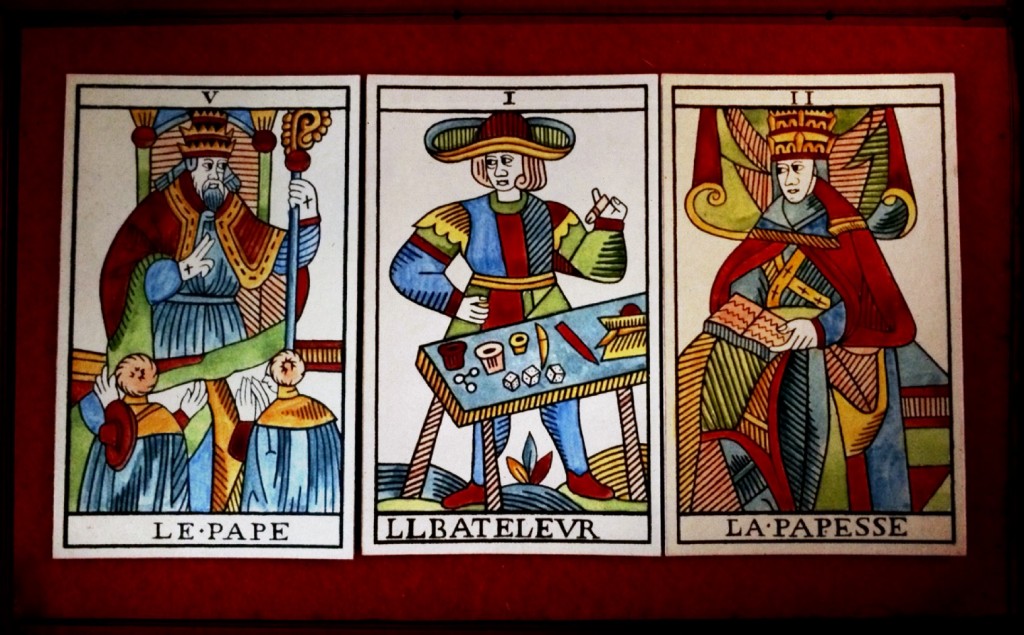 three tarot cards -- The Pope, The Magician, The Popess - face up on a field of red