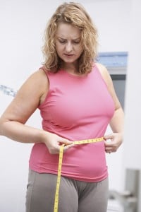 Frustrated Overweight Woman Measuring Waist In Bathroom