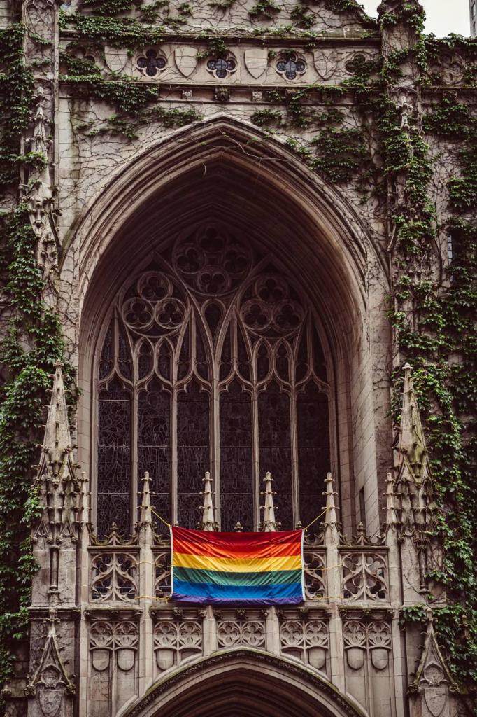 A Pride Rainbow Flag hangs outside of a church.