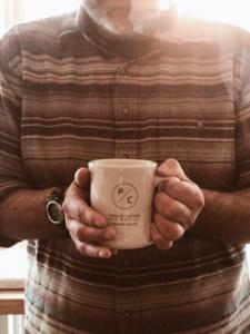 Owner of Coffeehouse hold a cup of coffee.