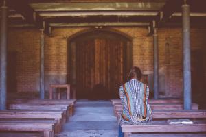 Girl sitting inside wooden church.