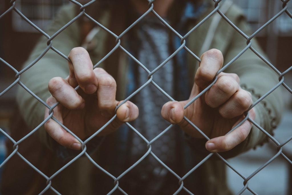 Man standing behind a chainlink fence.