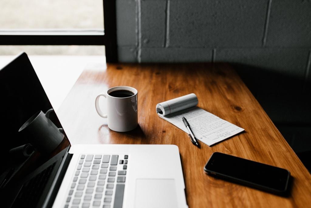 Photo by Andrew Neel on Unsplash Cup of coffee, a MacBook, and a notebook