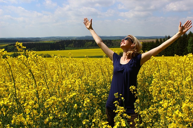 A photo of a woman praising God in a field. How do I know God loves me? The Bible has the answer!