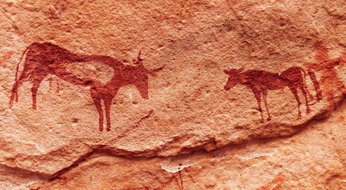 Ancient rock paintings in Sahara Desert, Tadrart, Algeria by Pichugin Dmitry. Image via Shutterstock.
