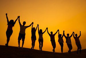 people raising their arms in triumph silhouetted by the setting sun