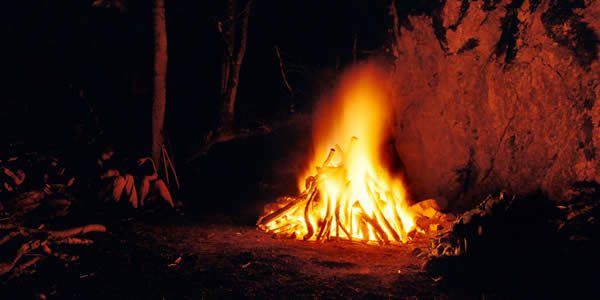 a couple seated next to a roaring campfire