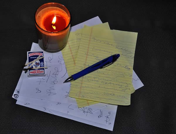 a pen, some paper, and a candle