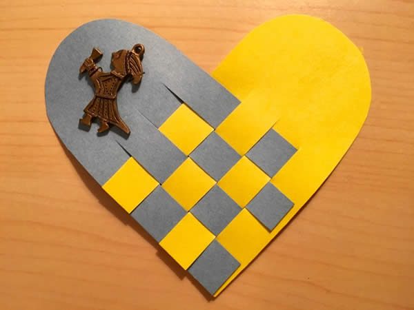 a paper heart constructed of gray and yello paper with a female figurine 