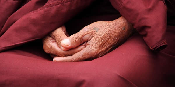 a close up of an old man's hands resting in his lap as he wears a robe