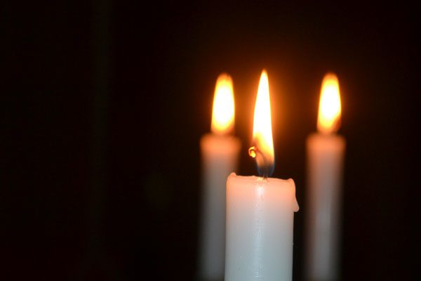 three lit candles in a dark room