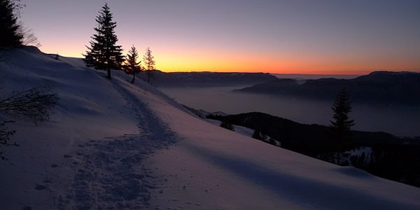 the sun rising over a snow covered medow