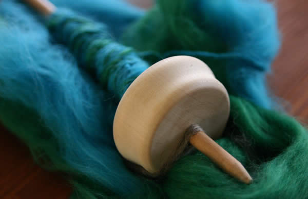 a spindle and blue-green wool