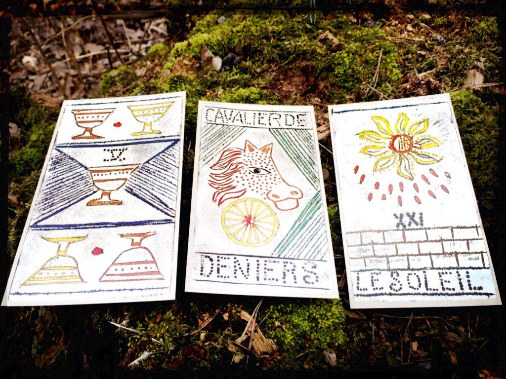 three tarot cards -- the 5 of cups, the knight of coins, and the sone -- placed on a mossy rock
