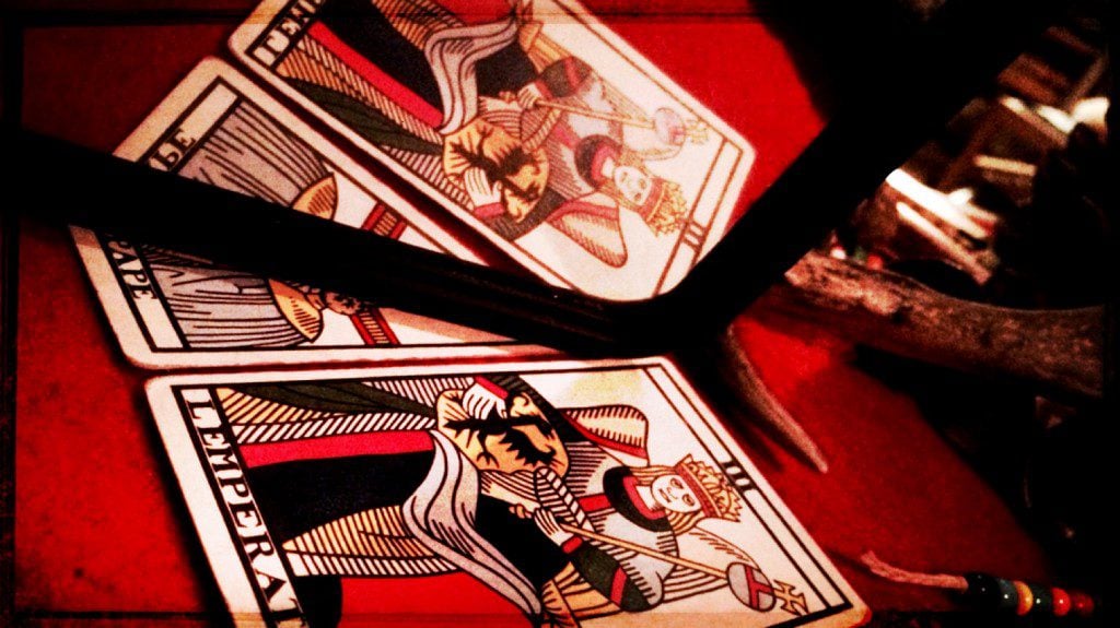 three tarot cards on a red table cloth