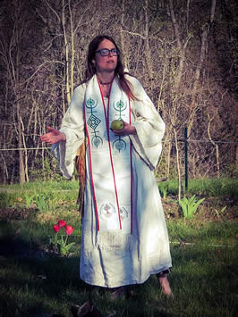 a woman stands in religious robes holding an apple