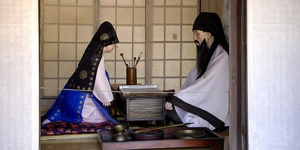 a young person in traditional, ceremonial garb neels before an ancestor shrine in Korea