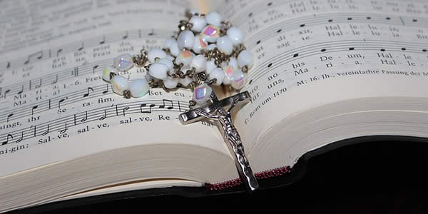 an open hymnal with a rosary on top of it