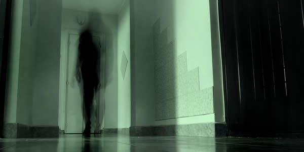 a photograph of a hallway with a shadowy figure at the end of it