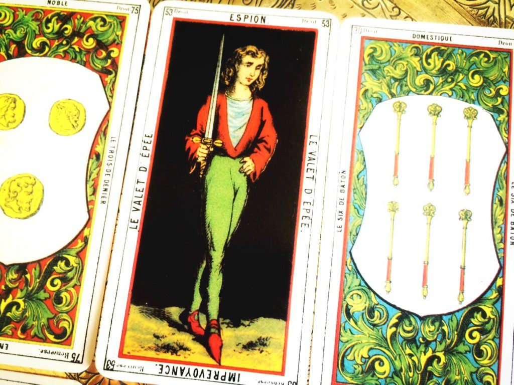 three cards face up -- the outer most cards are blurry but the center, focused card depicts a young woman holding a sword