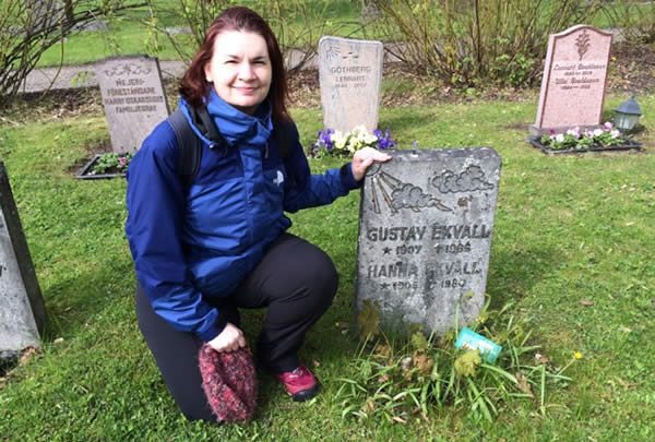 a woman kneels by a grave stone weathered with age