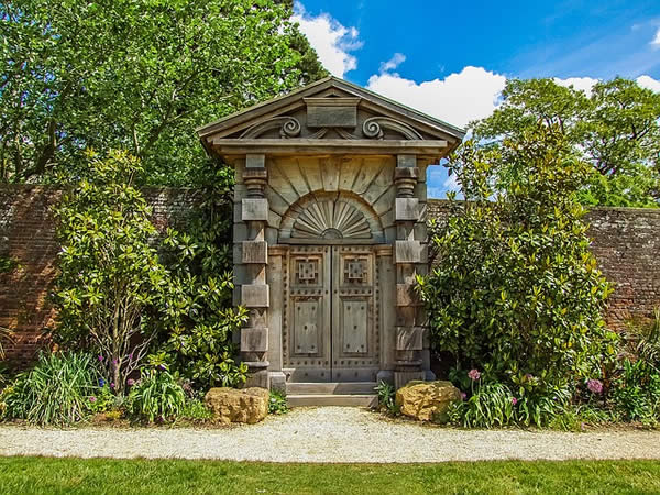 an ornate, human-sized stone door in a garden