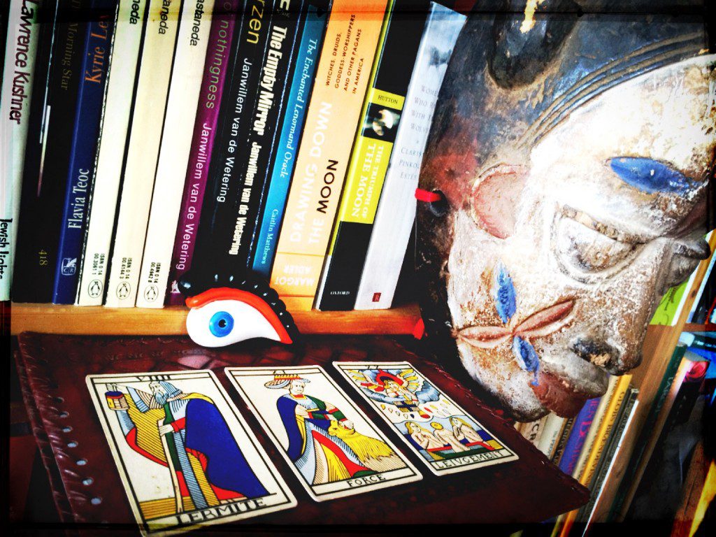 three tarot cards from the marseille tarot deck placed flat on a bookshelf