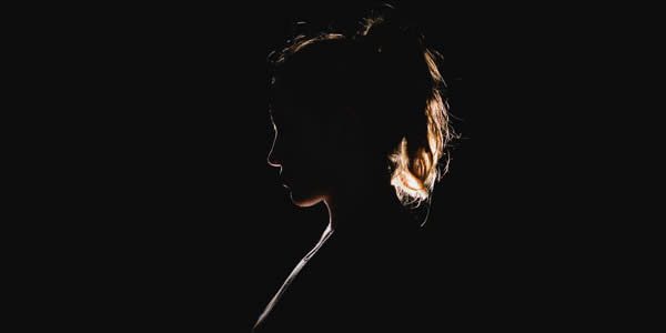 a backlit woman in a dark room