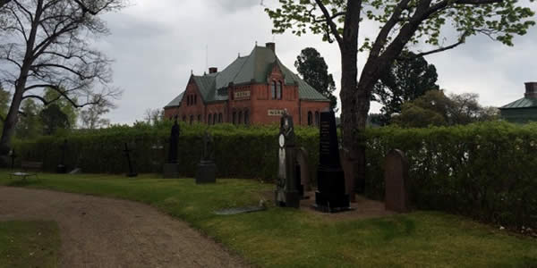 an exterior shot of a brick building with grave markers in the foreground