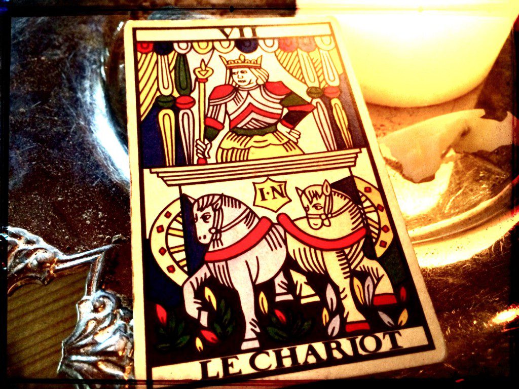 the chariot, a tarot card, on a table next to a lit candle