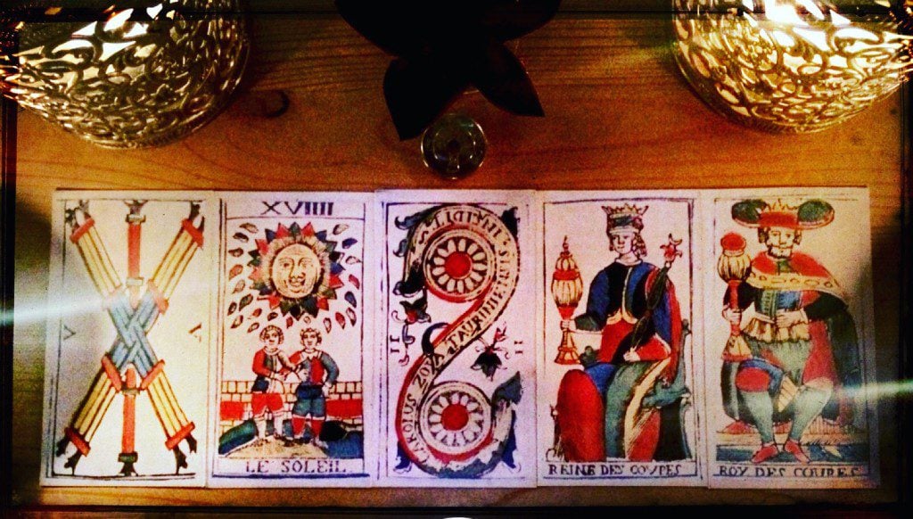 five tarot cards arranged on a table side to side