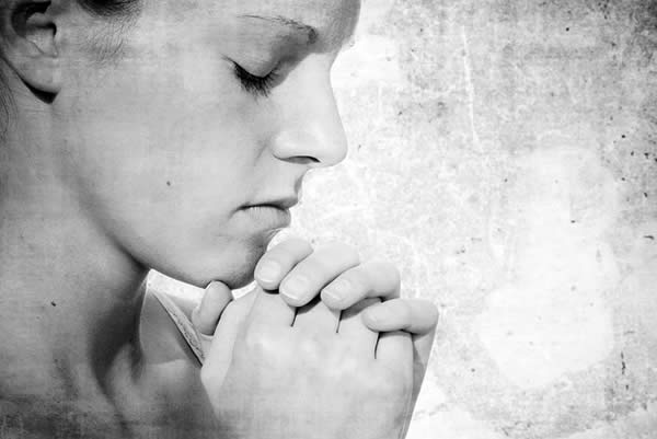 a woman clasping her hands before her in prayer