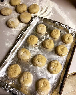 a baking sheet upon which small buns are being prepared. the buns have a run stamped on the top of them.