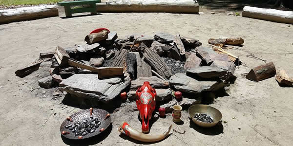 a collection of offering bowls on either side of a painted horse skull and drinking horn