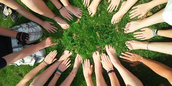 a group of caucasian young people placing their feet and hand together in a circle