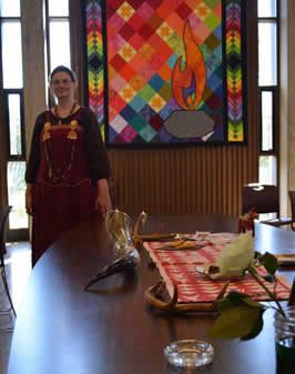 a woman in a ritual robe standing next to an altar