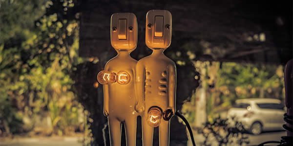 two humanoid figures, one with lightbulbs for breasts and the other with a lightbulb for a penis